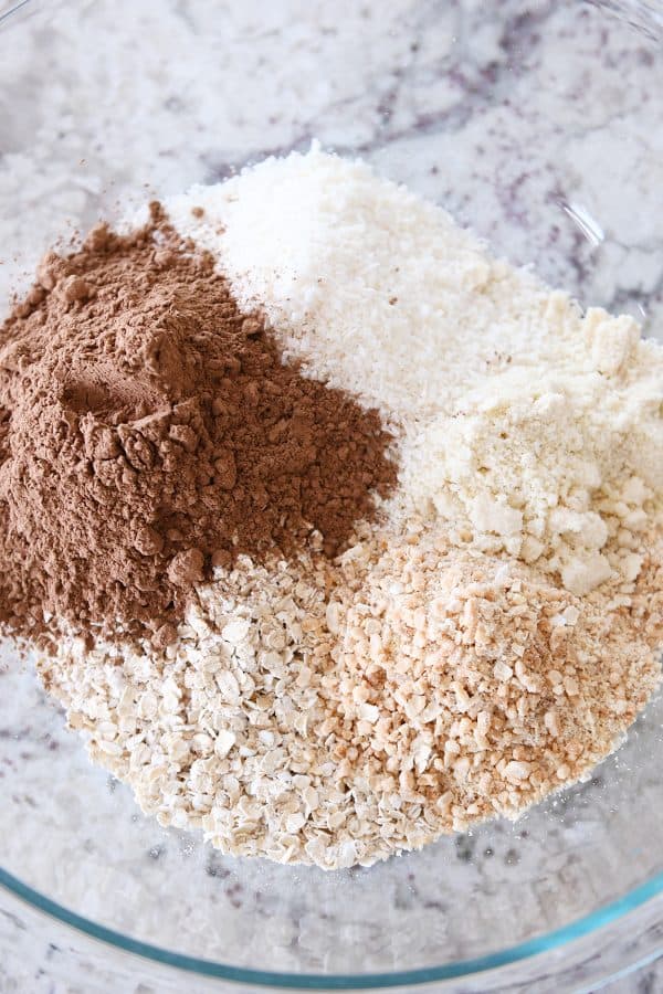 Dry ingredients for chocolate peanut butter granola bites in glass bowl.