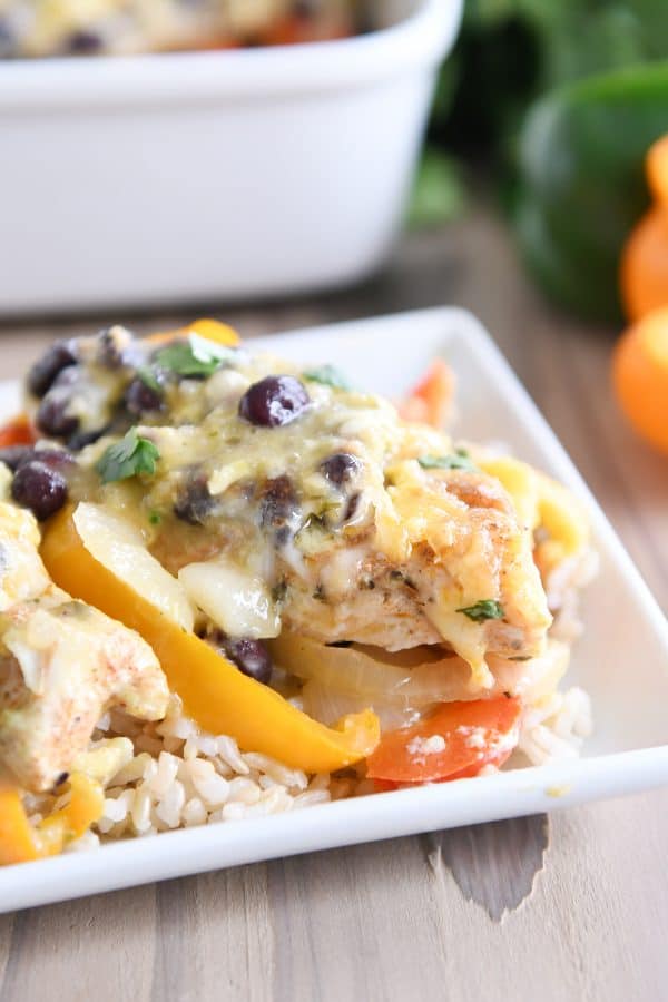 Cheesy chicken enchilada bake over brown rice on white platter.