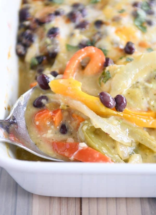 scooping up sauce and peppers from bottom of cheesy chicken enchilada bake