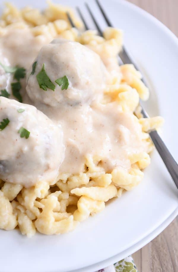 White plate with homemade German spaetzle noodles and meatballs.