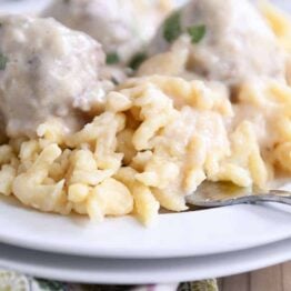 white plate with homemade German spaetzle noodles and meatballs and fork