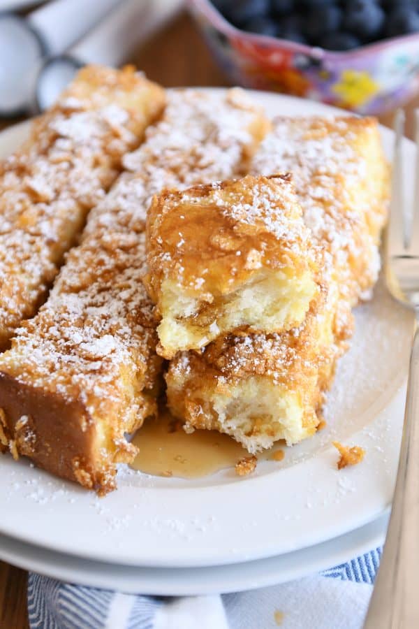 Crunchy baked french toast sticks with powdered sugar and syrup.