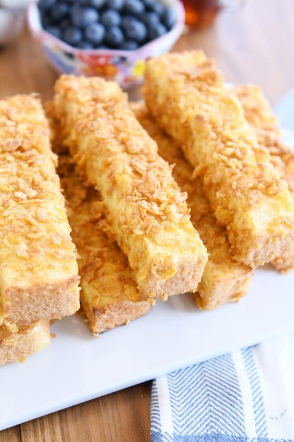 Crunchy baked french toast sticks on white platter.