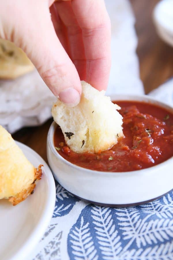 Dipping piece of pull-apart bubble bread in marinara sauce.