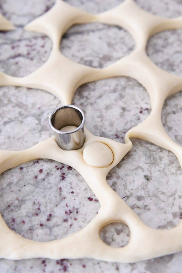 Cutting out more donut holes in homemade donut dough.