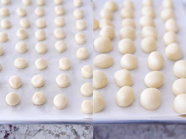 Donut holes rising on parchment lined baking sheet.