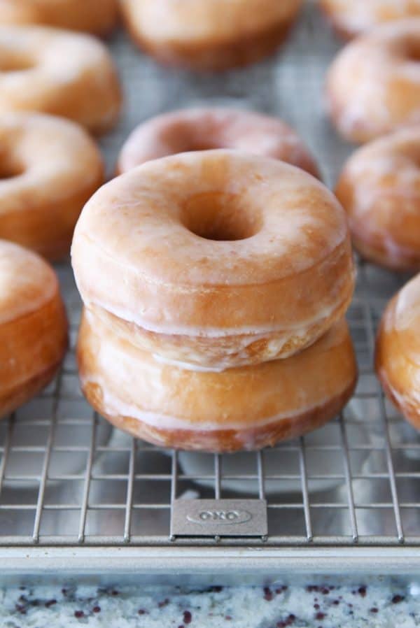 Stacked homemade glazed donuts on wire rack.