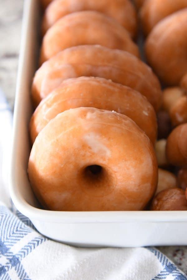 Homemade glazed donuts in white pan.