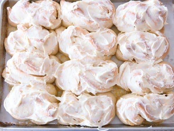 Baked and frosted homemade orange sweet rolls in twist shape.