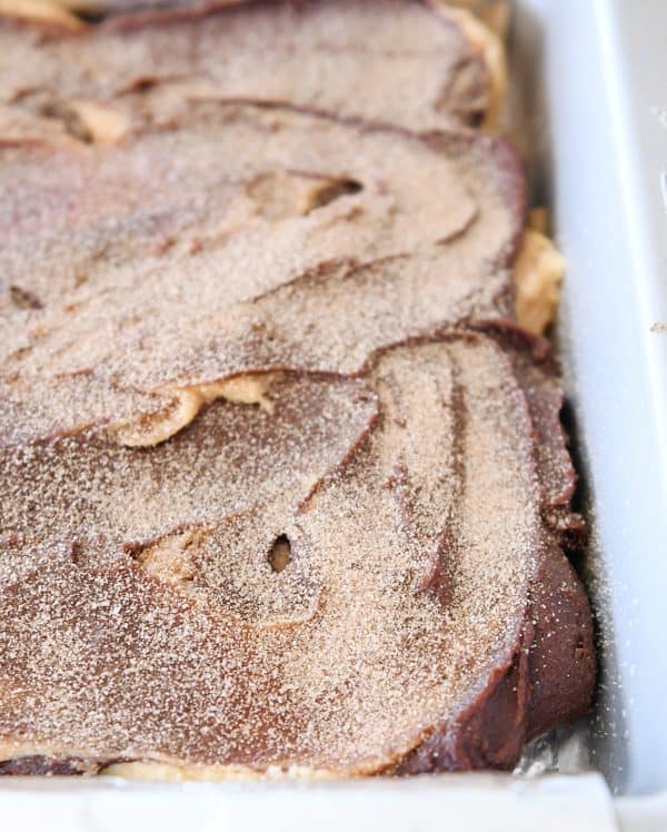 Cinnamon and sugar sprinkled on top of pan of snickerdoodle brookie bars.