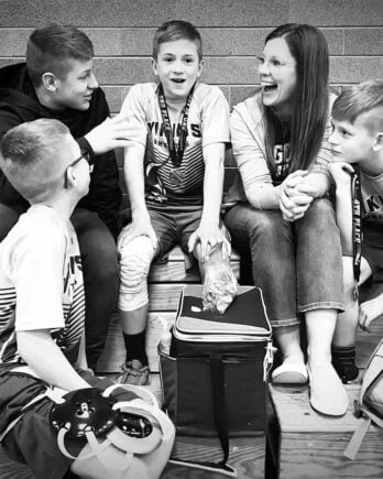 mom sitting in bleachers talking to her kids