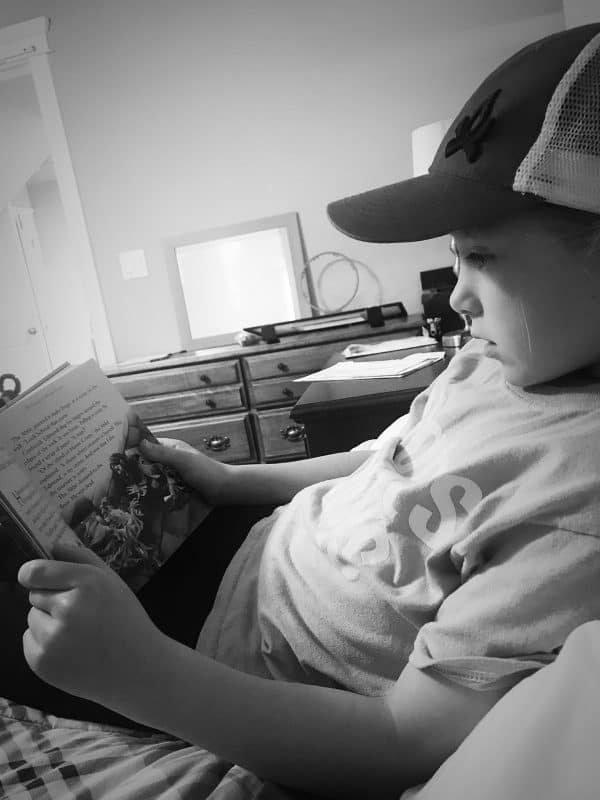 girl reading book on bed