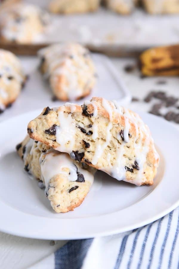 Two baked and glazed scones on white plate.