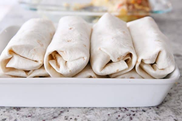 White baking pan with rolled freezer breakfast burritos.