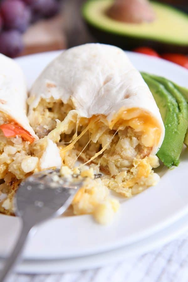 stringy cheese pulling away on easy freezer breakfast burritos on white plate