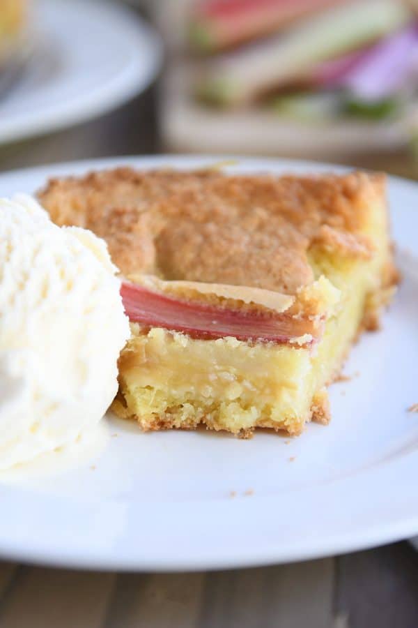 Rhubarb custard cake on white plate with ice cream.