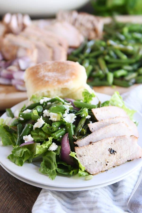 grilled pork salad with sliced pork and roll on white plate