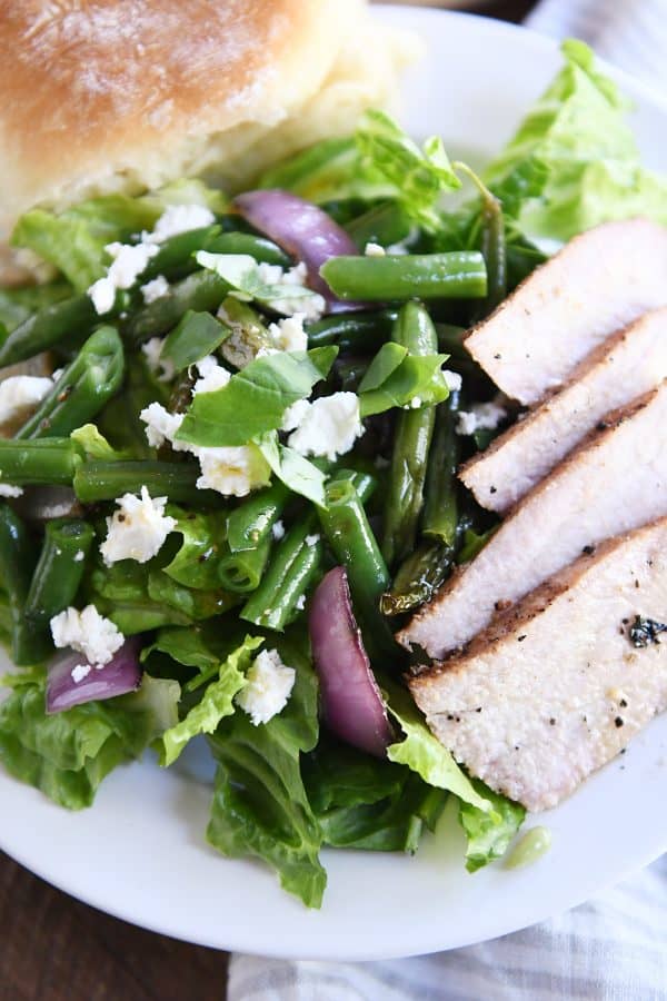 grilled pork and romaine, grilled onions, and feta cheese on white plate