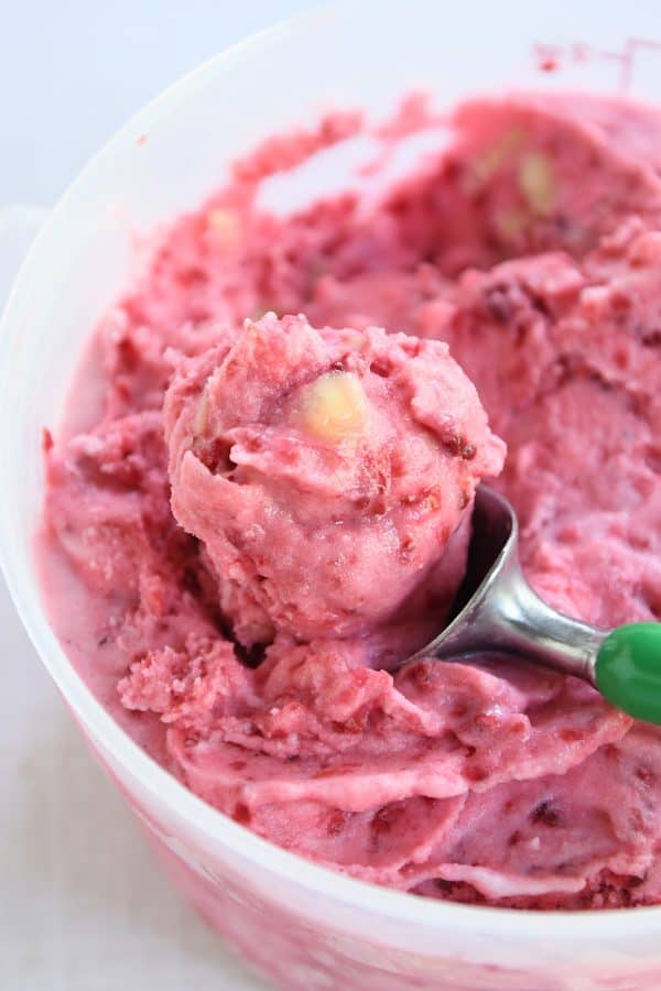 Ice cream scoop scooping out fruity pink sorbet.