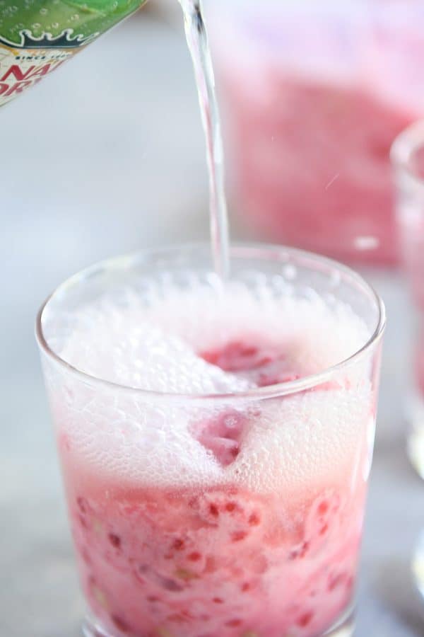 Pouring ginger ale into glass with frozen pink sorbet.