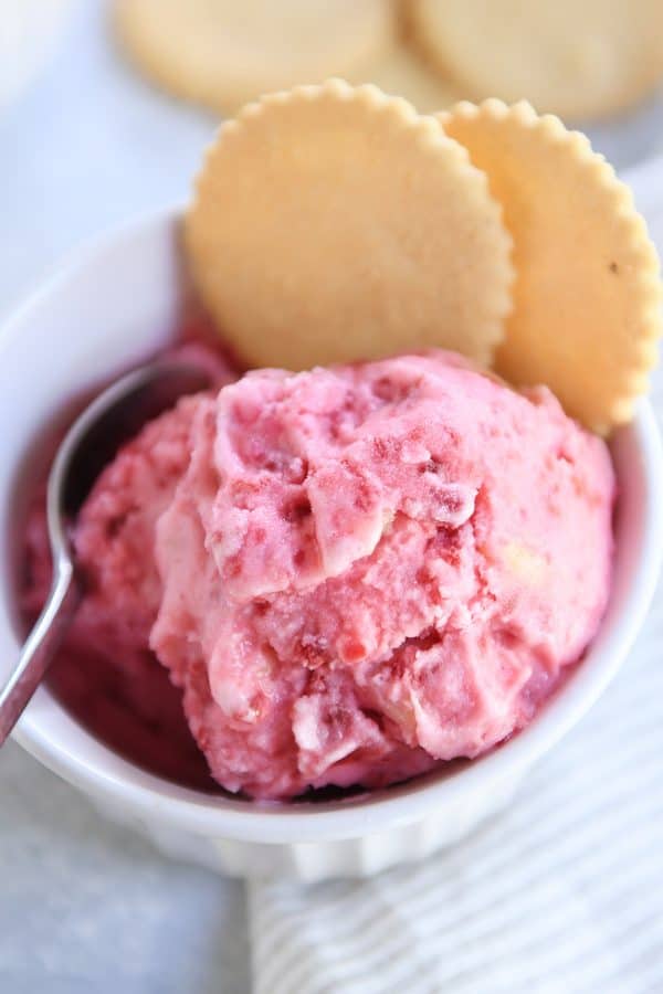 Close up view of pink sorbet in white dish with lemon cookies.