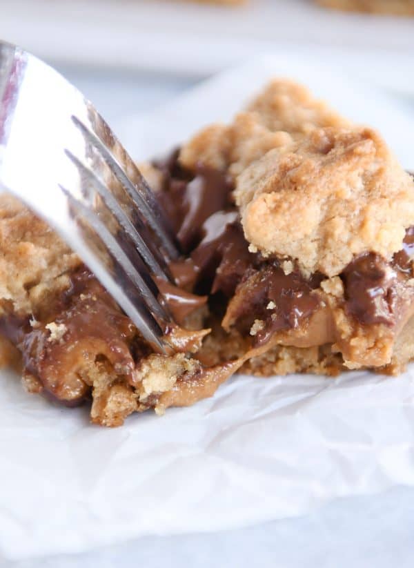 Fork taking bite out of warm caramel cookie bar.