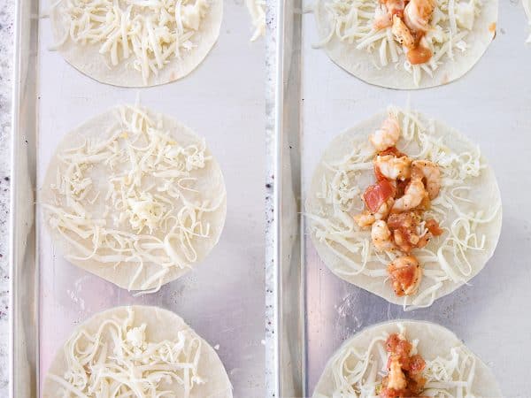 Flour tortillas on sheet pan with cheese and shrimp mixture for tacos.