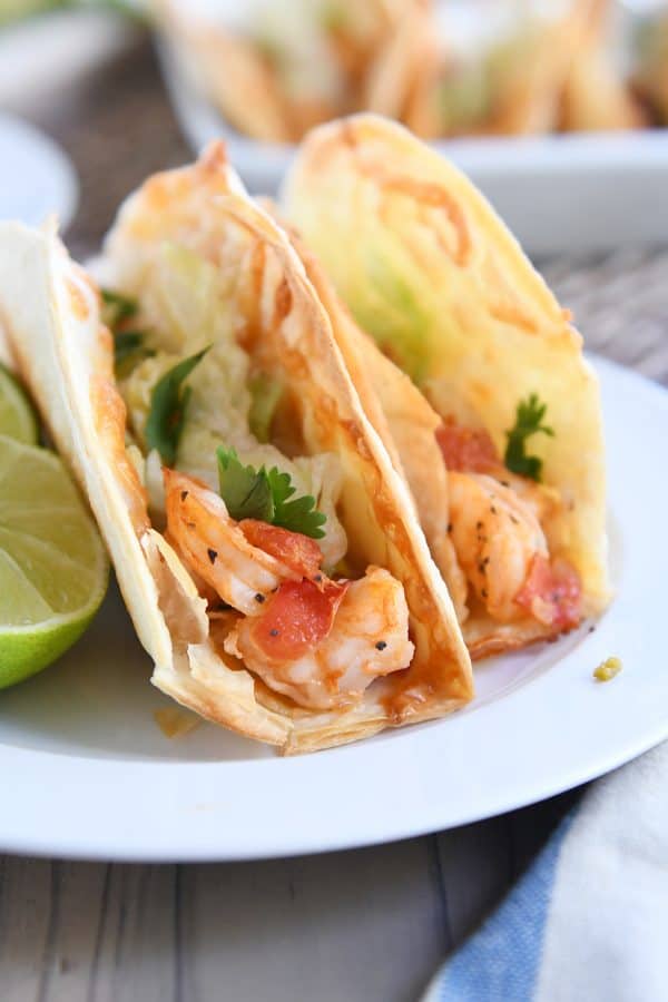 Two crispy shrimp tacos on white plate.