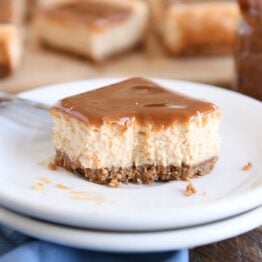 dulce de leche cheesecake square on white plate with bite taken out