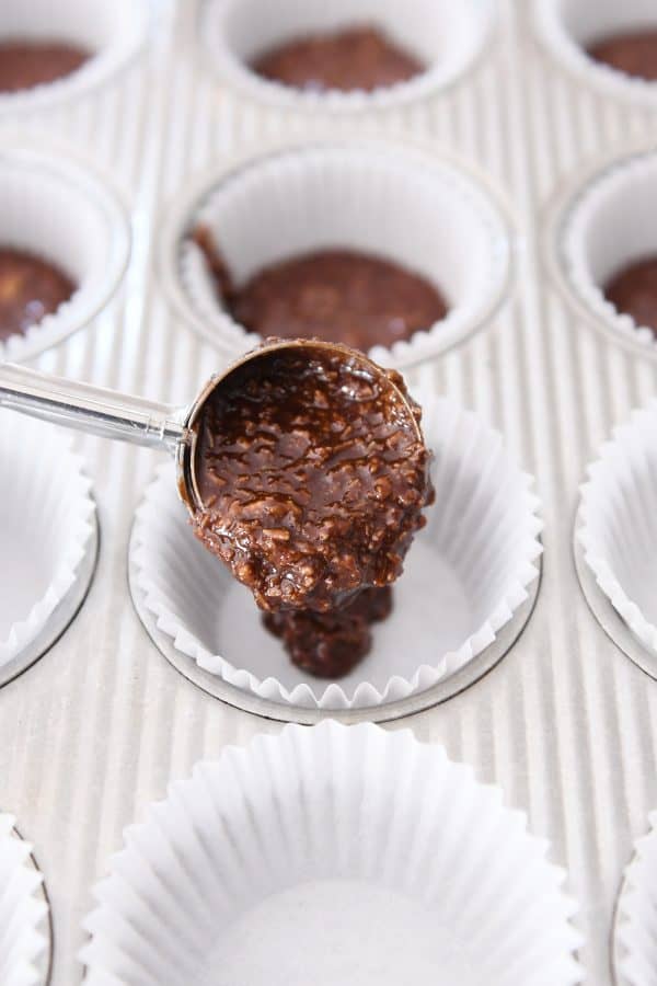 Scooping no-bake chocolate mixture into muffin liners.