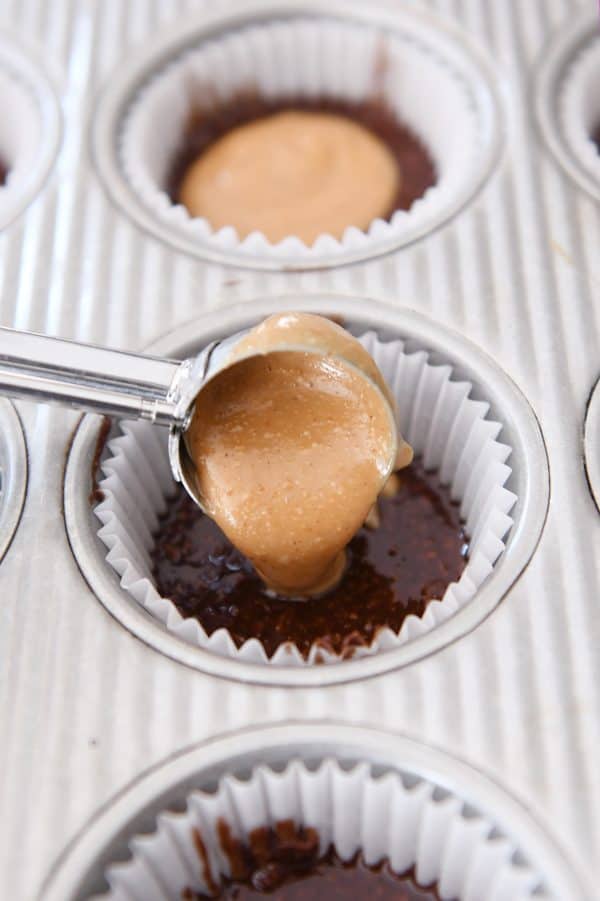 Scooping peanut butter mixture on top of no-bake chocolate mixture.