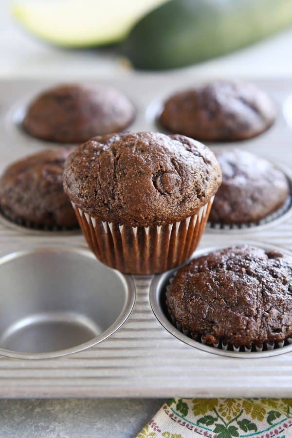 Baked chocolate zucchini muffin sitting on top of muffin tin pan.