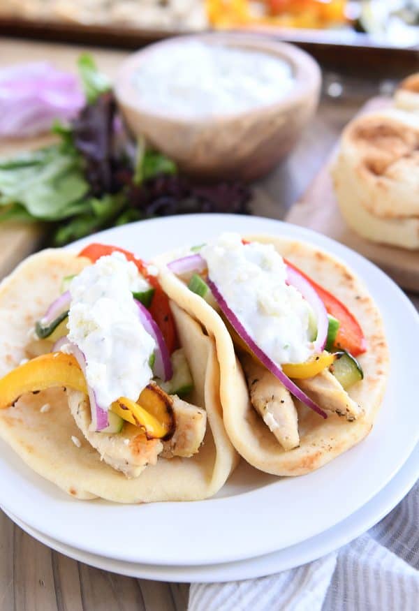 Two sheet pan chicken tzatziki wraps on white plate.