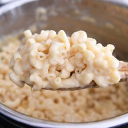 scooping up warm pressure cooker mac and cheese on wooden spoon