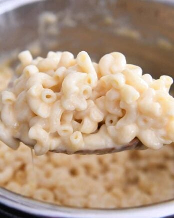 scooping up warm pressure cooker mac and cheese on wooden spoon