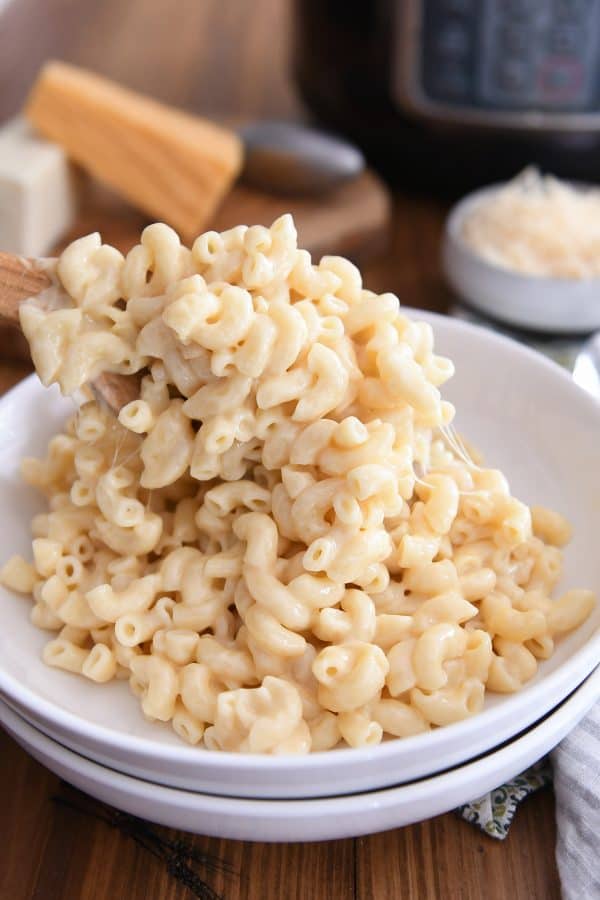 wooden spoon scooping mac and cheese into white bowl