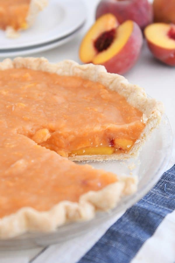 Fresh peach pie with slice removed.