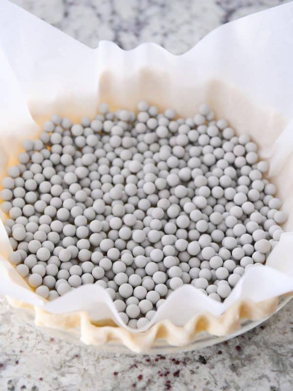 A pie crust covered with parchment and dry beans to get blind baked.