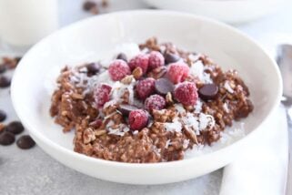 double chocolate steel cut oats in white bowl with coconut, chocolate chips and raspberries