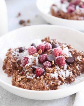 double chocolate steel cut oats in white bowl with coconut, chocolate chips and raspberries