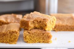 two pumpkin snickerdoodle bars stacked on white tray with bite taken out of top bar