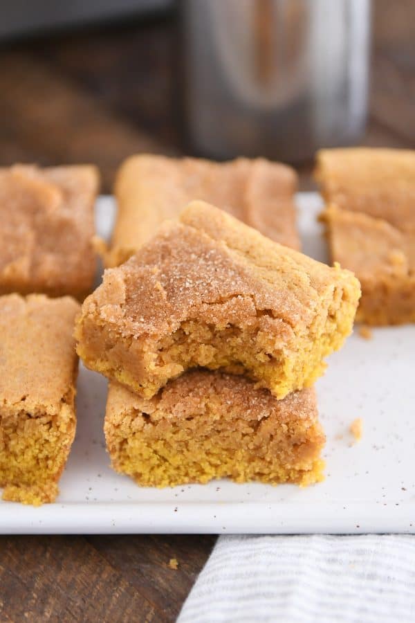 two pumpkin snickerdoodle bars stacked on white tray with bite taken out of top bar