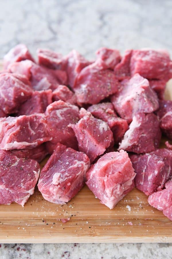 Raw beef chunks on cutting board.