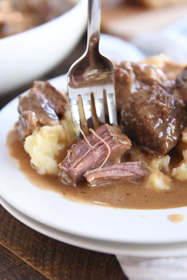 Fork with tender beef tips and gravy on mashed potatoes.