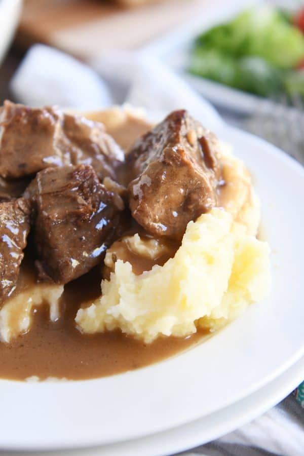 Slow cooker smothered beef tips and gravy on mashed potatoes.