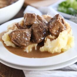 smothered beef tips and mashed potatoes on white plate