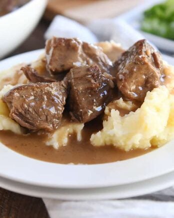 smothered beef tips and mashed potatoes on white plate