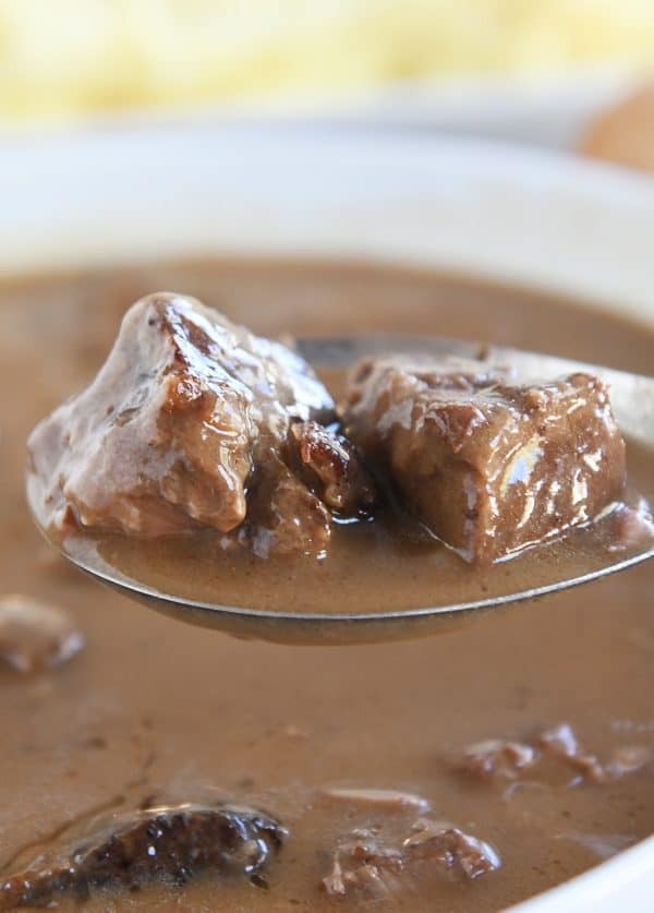 Spoon scooping smothered beef tips and gravy.