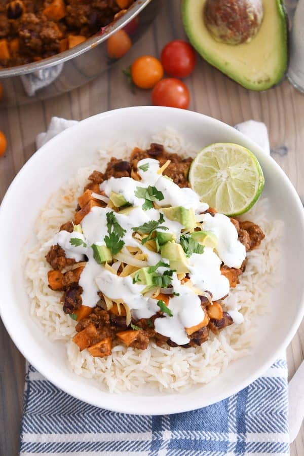 white rice topped with sweet potato black bean burrito ingredients, avocados, cilantro and limes