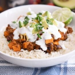 white rice topped with sweet potato black bean burrito ingredients, avocados, cilantro and limes